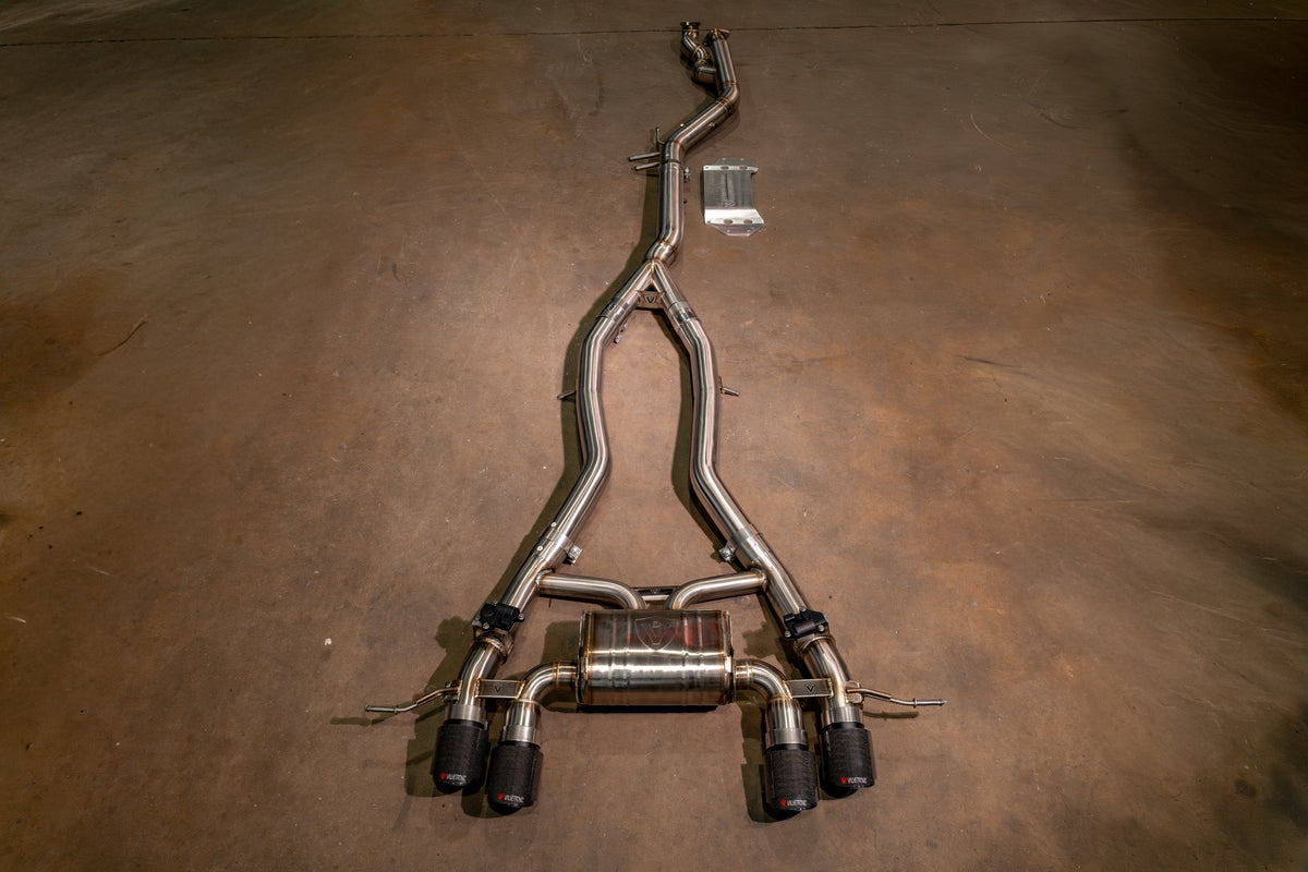 BMW G80/G82/G83 M3 / M4 valved sport exhaust system in polished stainless steel, with branched pipes and four black tips.