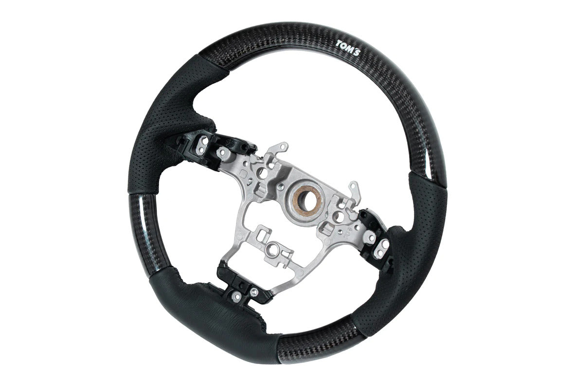 TOM'S Steering Wheel (Carbon)OEM factory replacement for Toyota GR Yaris & GR Corolla- OEM switches and airbag can be used- High-quality perforated black leatherSteering WheelTOM's Racing
