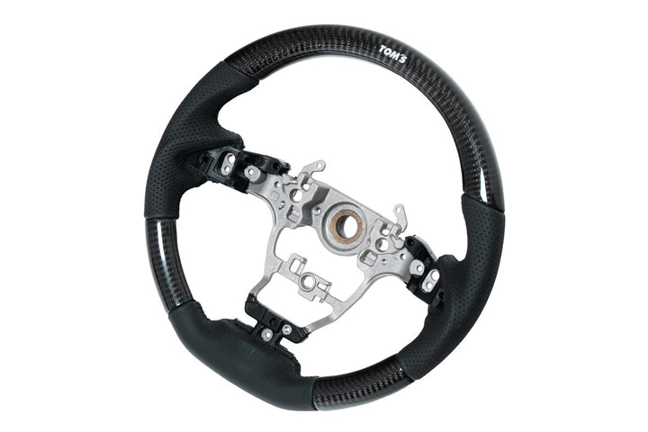 TOM'S Steering Wheel (Carbon)OEM factory replacement for Toyota GR Yaris &amp; GR Corolla- OEM switches and airbag can be used- High-quality perforated black leatherSteering WheelTOM's Racing